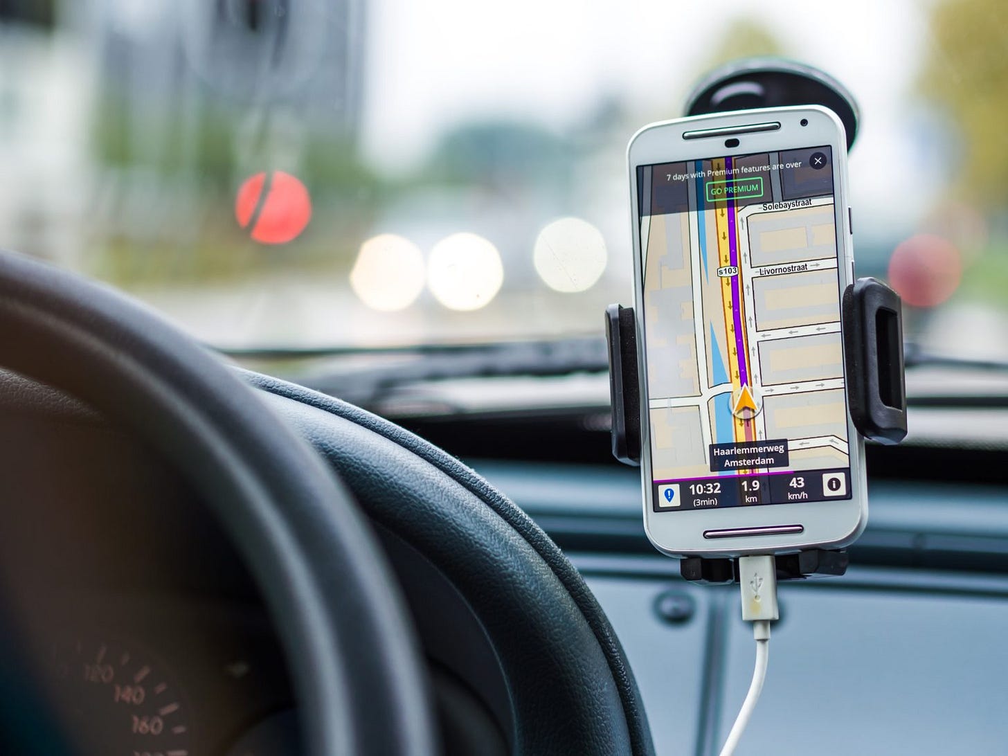 A picture of a smart phone attached to a car windscreen by a holder. It is showing a map