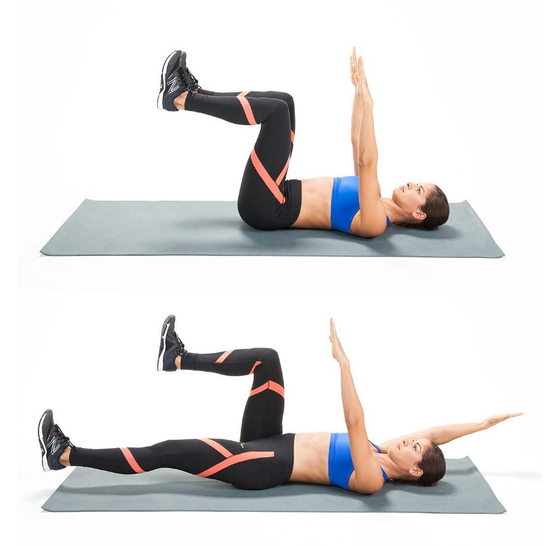 A side view of a woman on her back doing the dead bug exercise with her arms and legs in the air