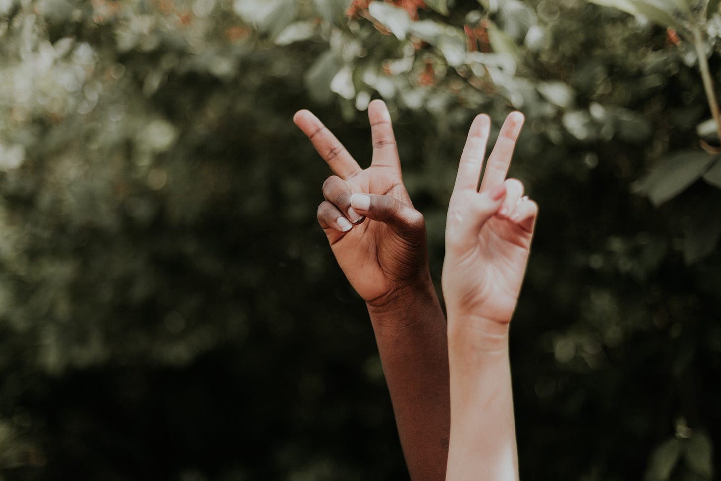 Two people are holding their hands up in the air with the two finger peace sign
