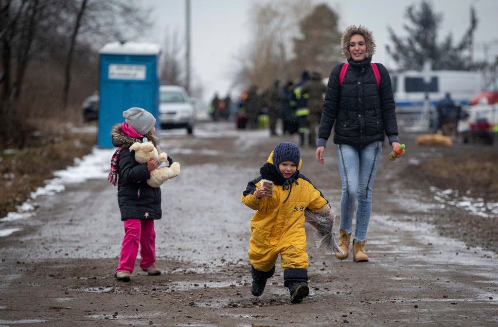 Children, followed by a woman, run as they arrive at the border crossing in Medyka, Poland, after fleeing Ukraine, Wednesday, March 9, 2022.