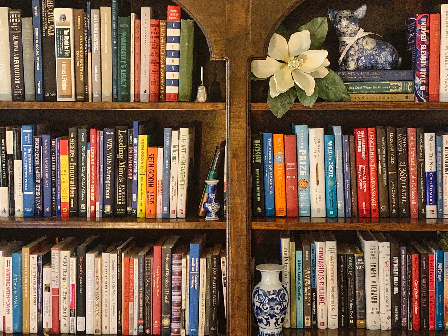 a book shelf with three rows of books and a few knick-knacks stuck in between