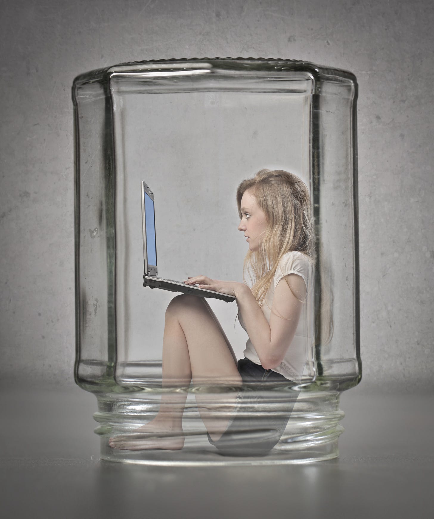 A female writer with a laptop trapped under a bell jar that for some reason is just an ordinary jam jar, go figure