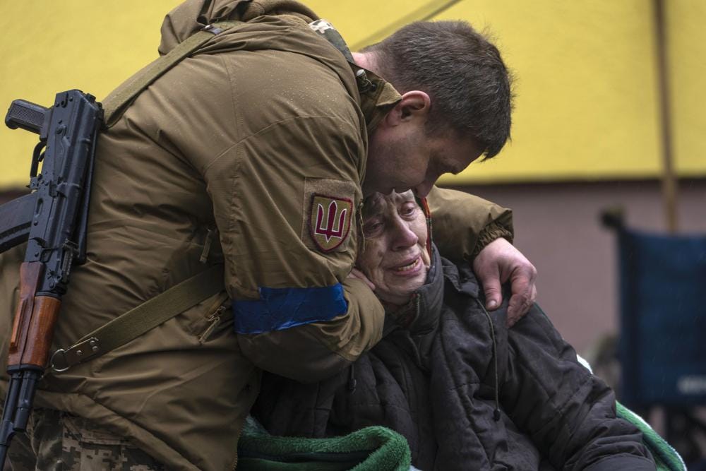 A soldier comforts Larysa Kolesnyk, 82, after she was evacuated from Irpin, on the outskirts of Kyiv, Ukraine, Wednesday, March 30, 2022. (AP Photo/Rodrigo Abd)