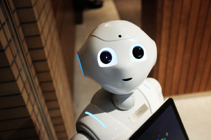 A photo of a white plastic robot with a humanoid smile