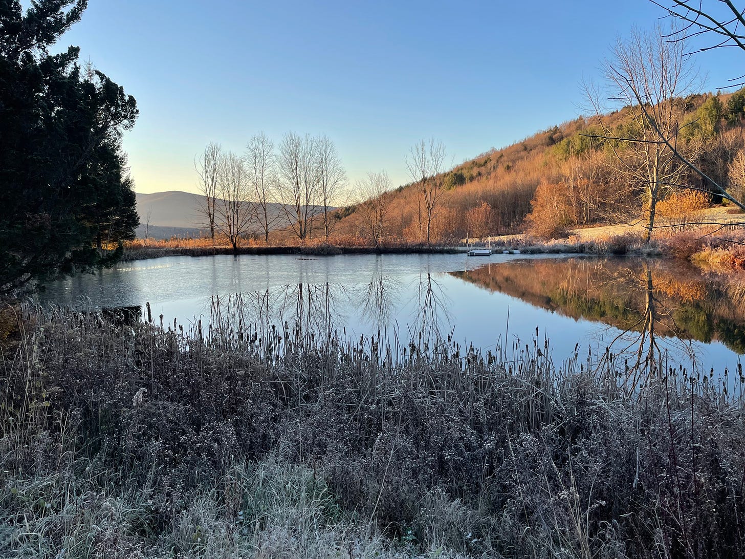 a pond half-frozen with mountain beyond