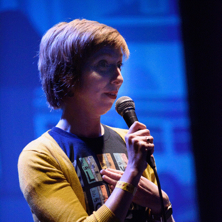 An animated gif with five photos of ilyse iris magy holding a microphone, performing at Muni Diaries Live in November 2022. Photos by Emily Huston.