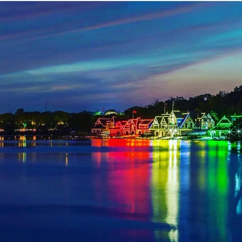 Rainbow-colored lights from Philadelphia's boathouse row reflected in Schuylkill River at dusk for Gay Pride Month 2018.