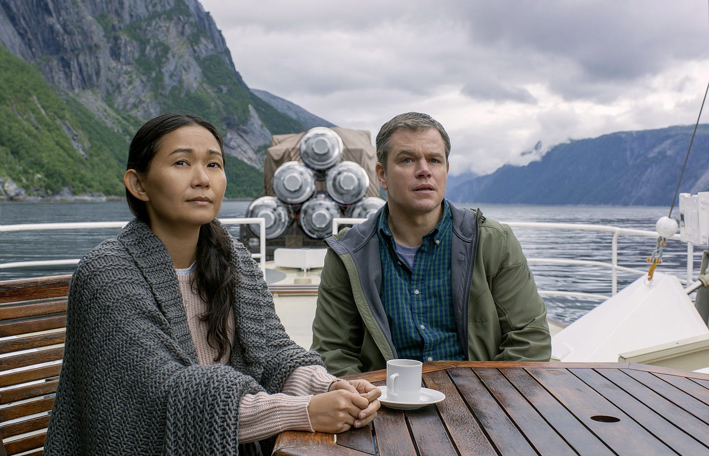 Hong Chau and Matt Damon sit on a barge in a scene from Downsizing