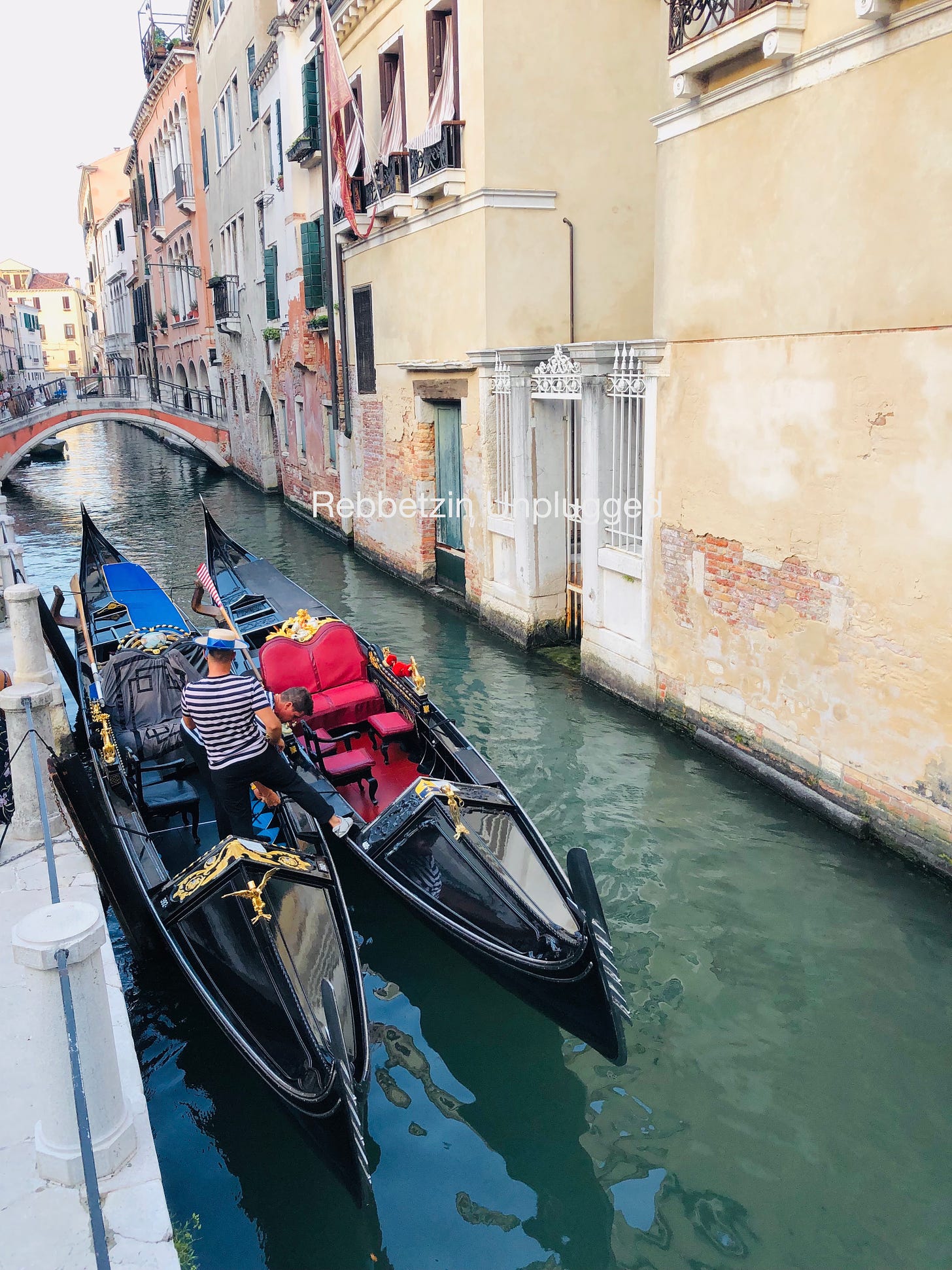 Gondoliers tying their gondola boats near a bridge on a canal in Venice, Italy