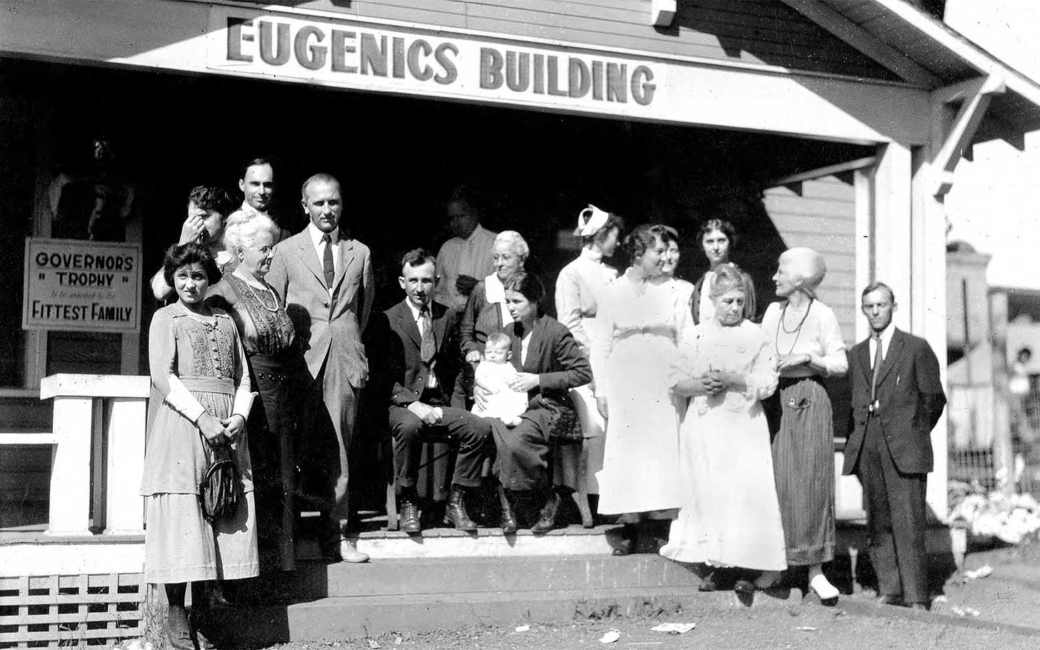 Black and white photo of a group of people standing outside a structure with a sign that reads "Eugenics Building."