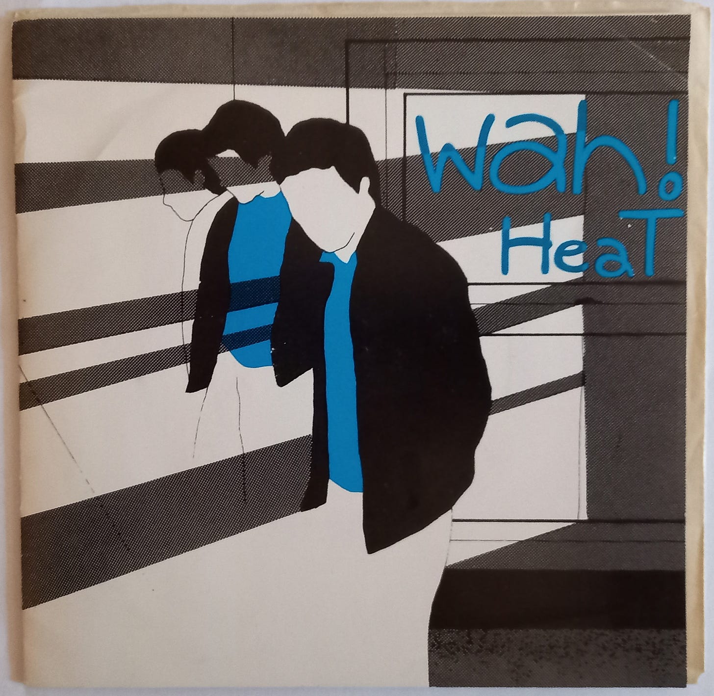 A seven-inch record sleeve. The design is black, white and blue with a drawing of three young men and the words "Wah! Heat".