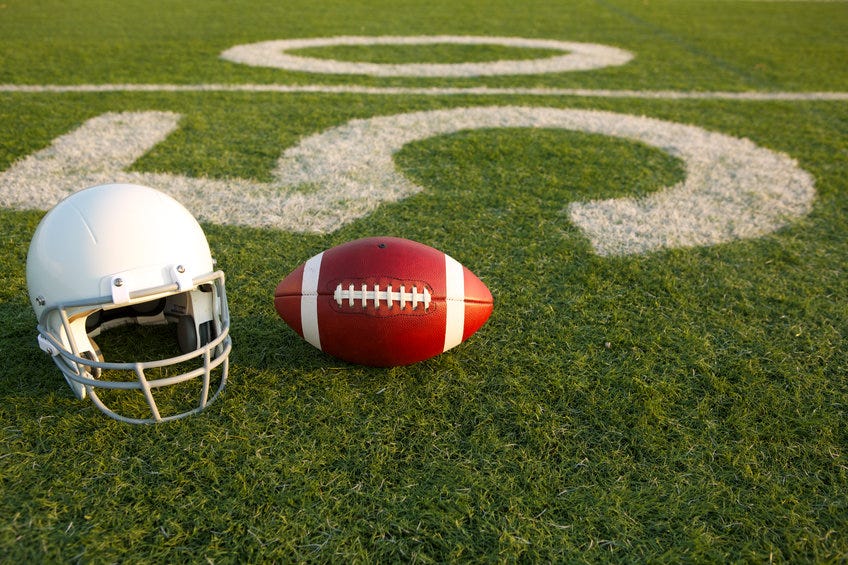 Football and white helmet on 50-yard line