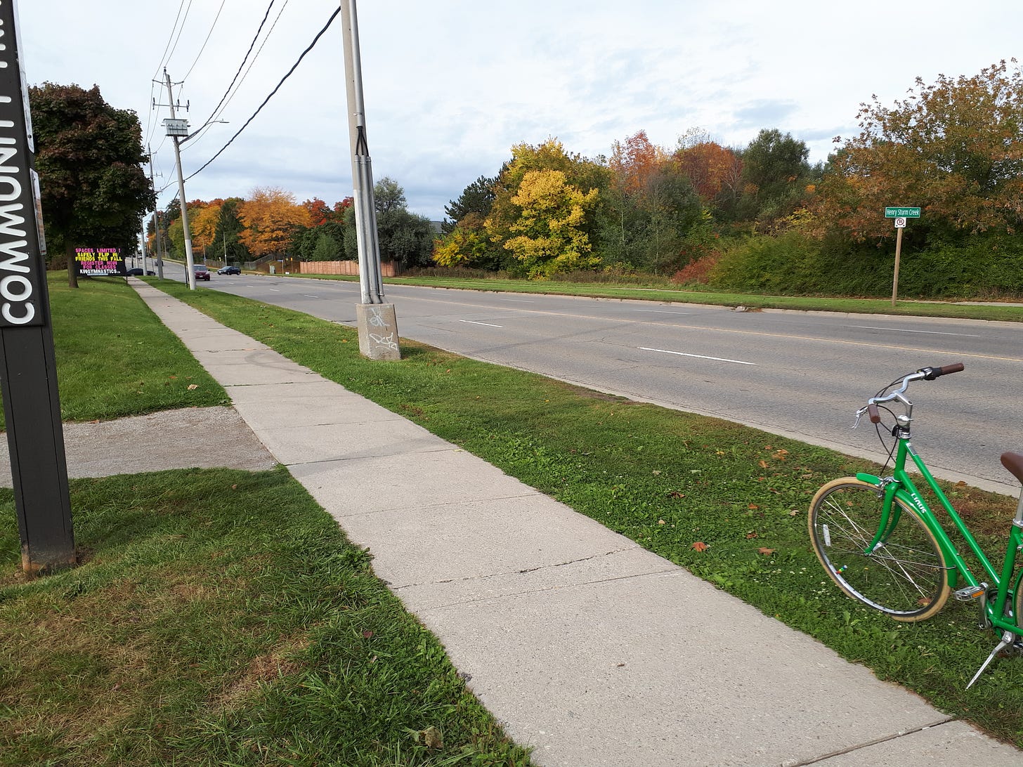 Sidewalk leading to a community trail. Green bike sitting beside the sidewalk.