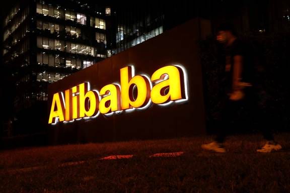 A man walks past a logo of Alibaba Group at its office building in Beijing, China August 9, 2021. REUTERS/Tingshu Wang/File Photo