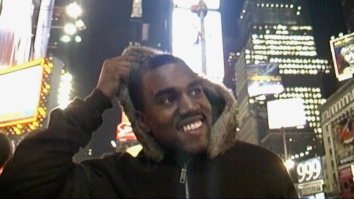 Kanye walking through Time Square in a still 