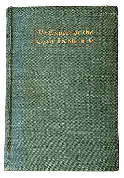 A green, cloth-covered book with the words The Expert at the Card Table embossed on it