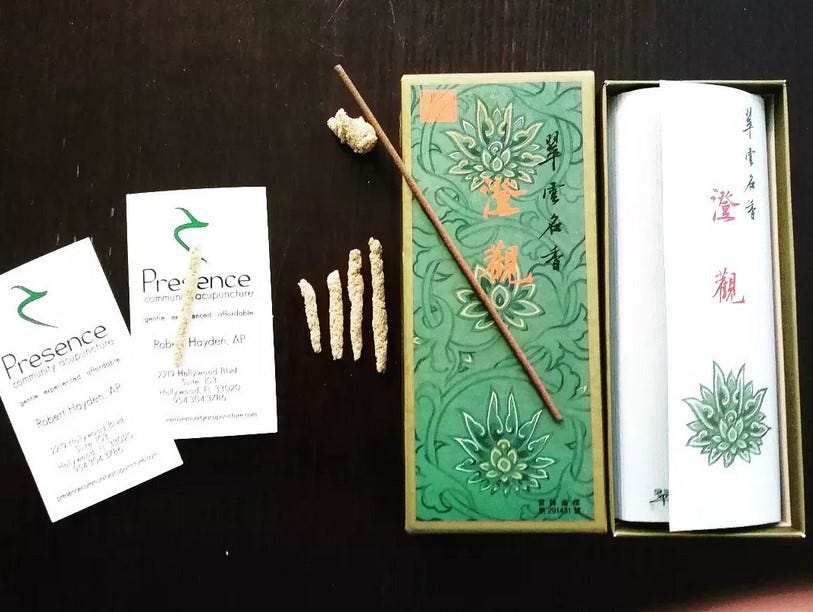 Photo of moxibustion kit with rolled moxa, incense sticks and rolling cards.