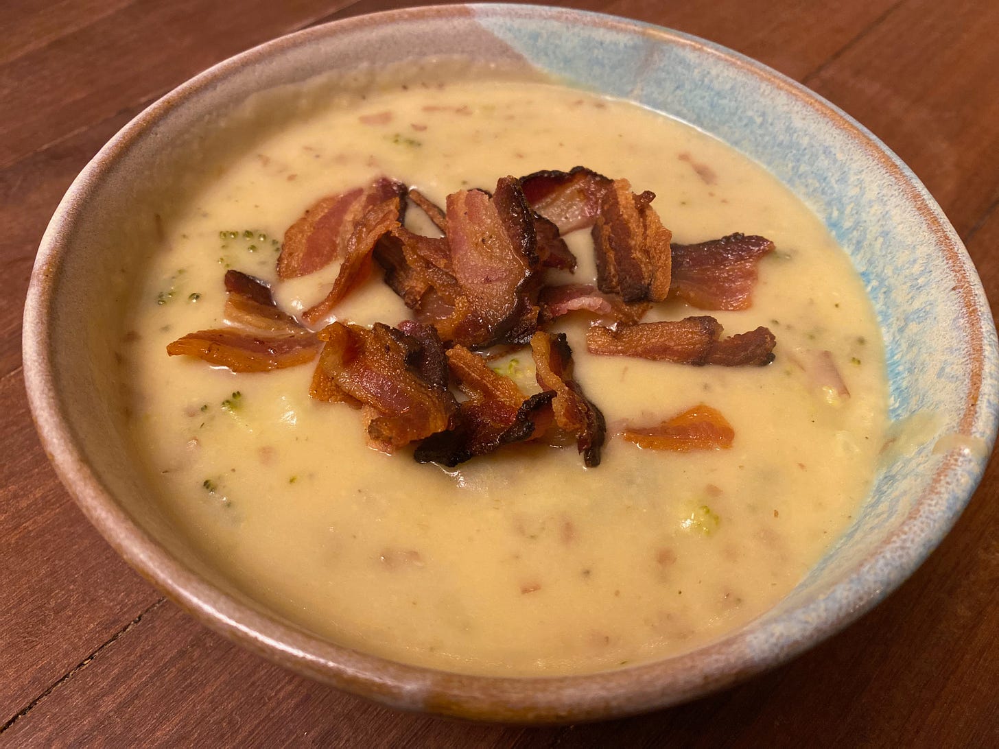 A ceramic bowl of creamy potato soup topped with a pile of crispy bacon.