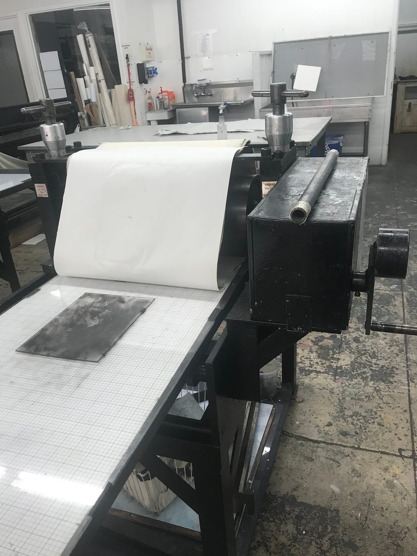 Documentation of intaglio process.  The image shows a large etching prress with an inked plate.