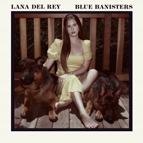 Capa do álbum Blue Banisters com Lana Del Rey usando vestido amarelo e sentada no chão com uma cara triste entre dois grandes cães