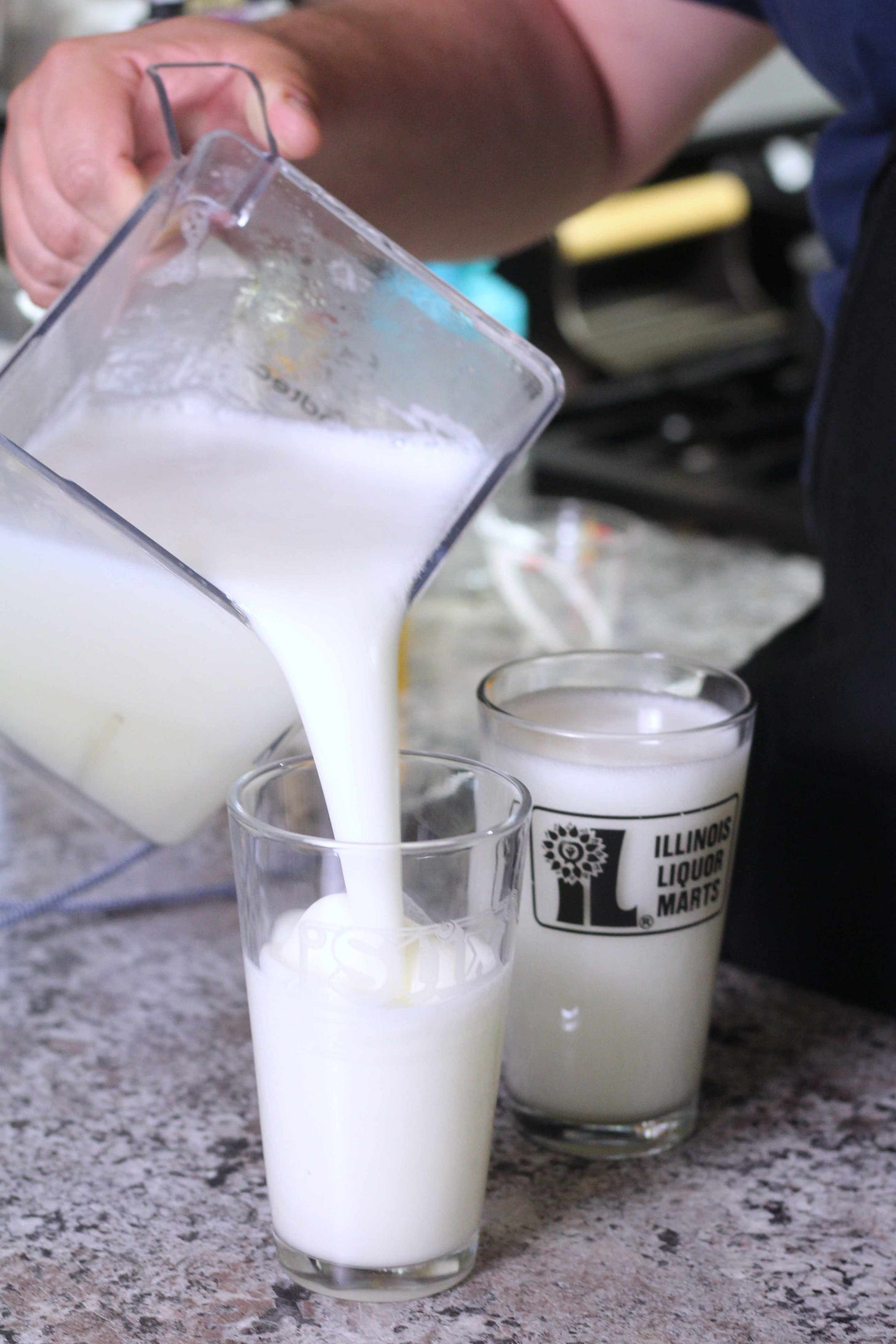 blender pitcher with frozen lemonade being poured into glasses