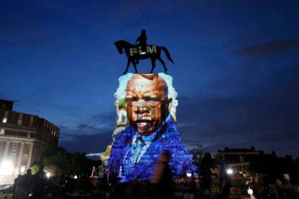 An image of the late Georgia Congressman and civil rights pioneer U.S. Rep. John Lewis is projected on to the pedestal of the statue of confederate Gen. Robert E. Lee on Monument Avenue, Wednesday, July 22, 2020, in Richmond, Va. The statue has become a focal point for the Black Lives Matter protests in the area. (AP Photo/Steve Helber)