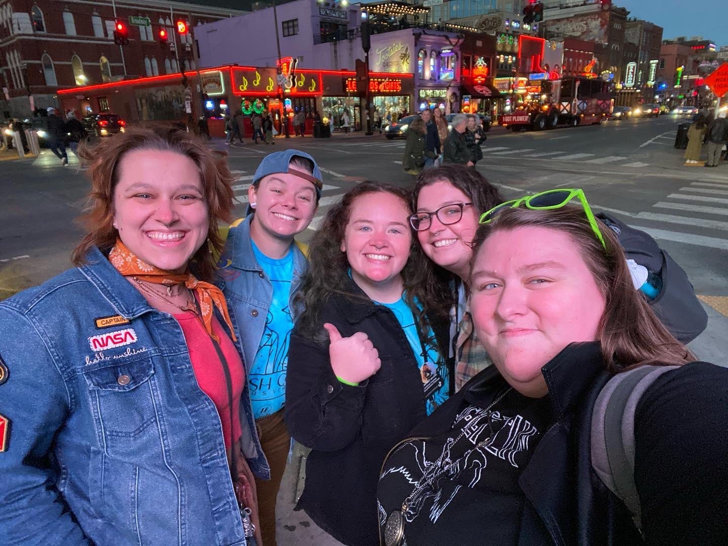 A group of five joyful queer friends smiling on a colorful street in Nashville.