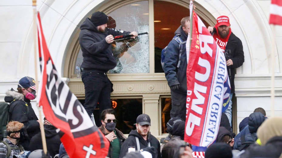 A man breaks a window as a mob of supporters of U.S. President Donald Trump storm the U.S. Capitol Building in Washington, January 6, 2021.
