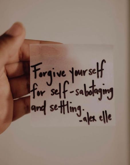 A hand holding out a post-it note with the following words written in black sharpie on it: "Forgive yourself for self-sabotaging and settling. - alex elle"
