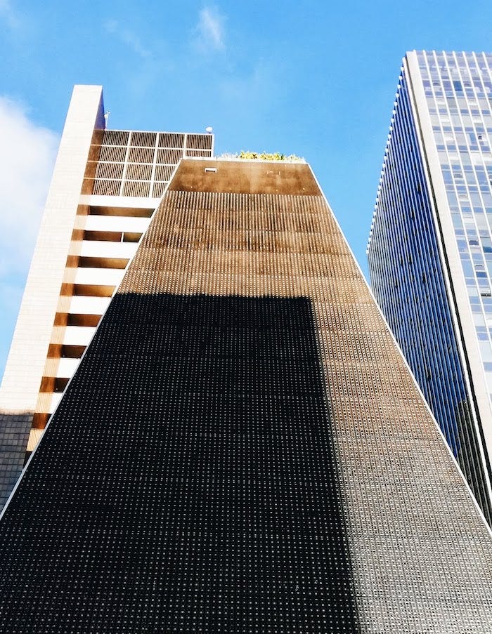 Foto mostra prédio preto em formato triangular em contraste com céu azul.