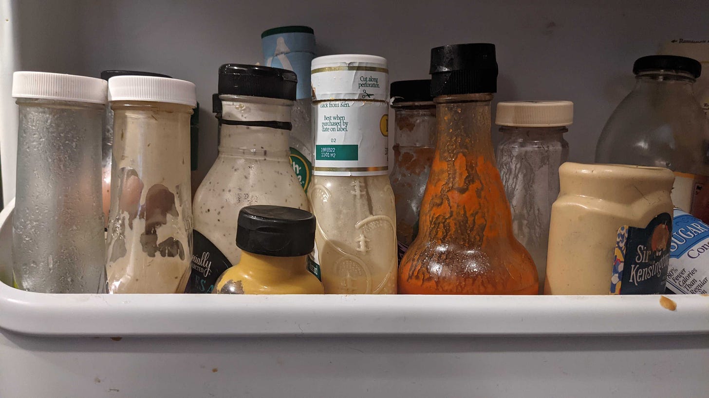 A collection of assorted salad dressings packed into the door shelf of a fridge. 