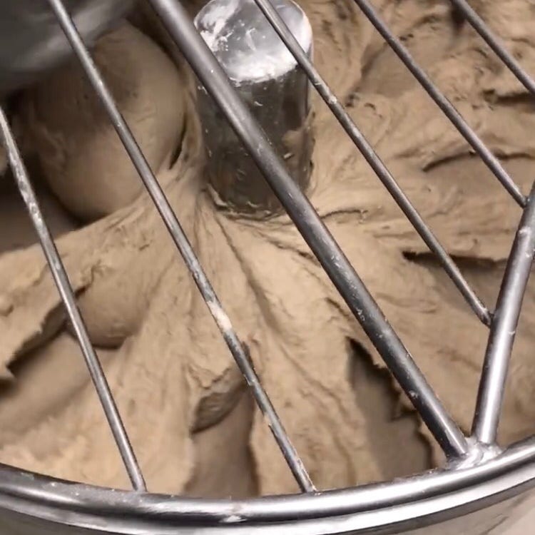 Dough that still clings to the walls of the mixing bowl, creating a web-like appearance as it sticks to the center of the mixer and the sides of the mixing bowl.