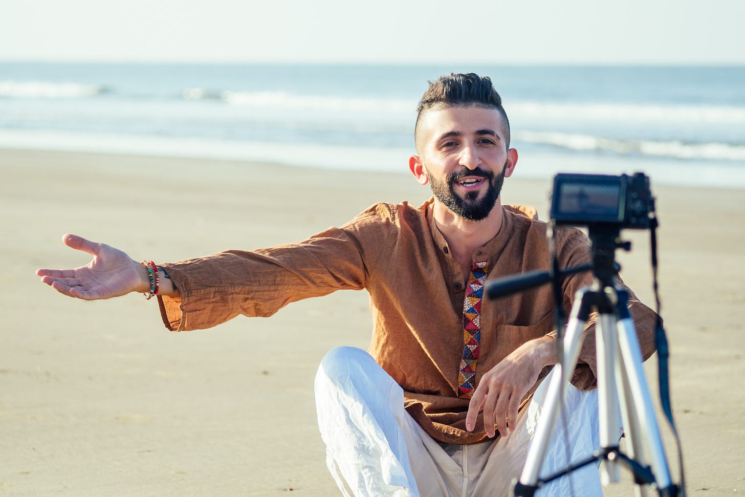 man on the beach filming on a cellphone mounted on a tripod