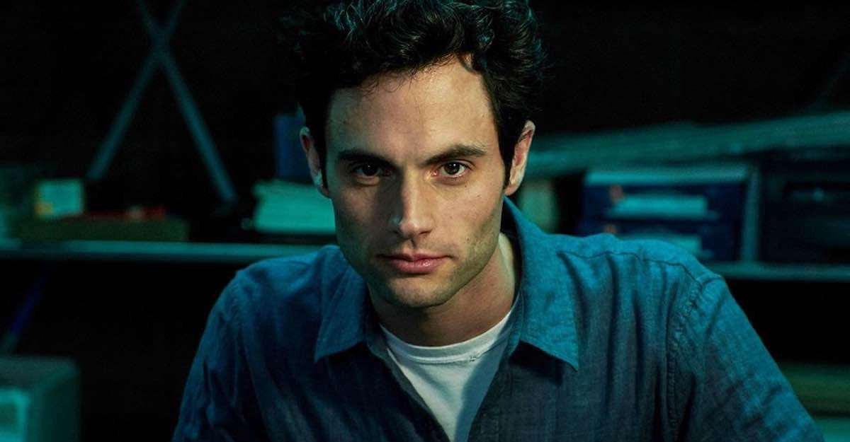 Joe Goldberg, played by Penn Badgley, stares intensely into the camera against a darkened background.