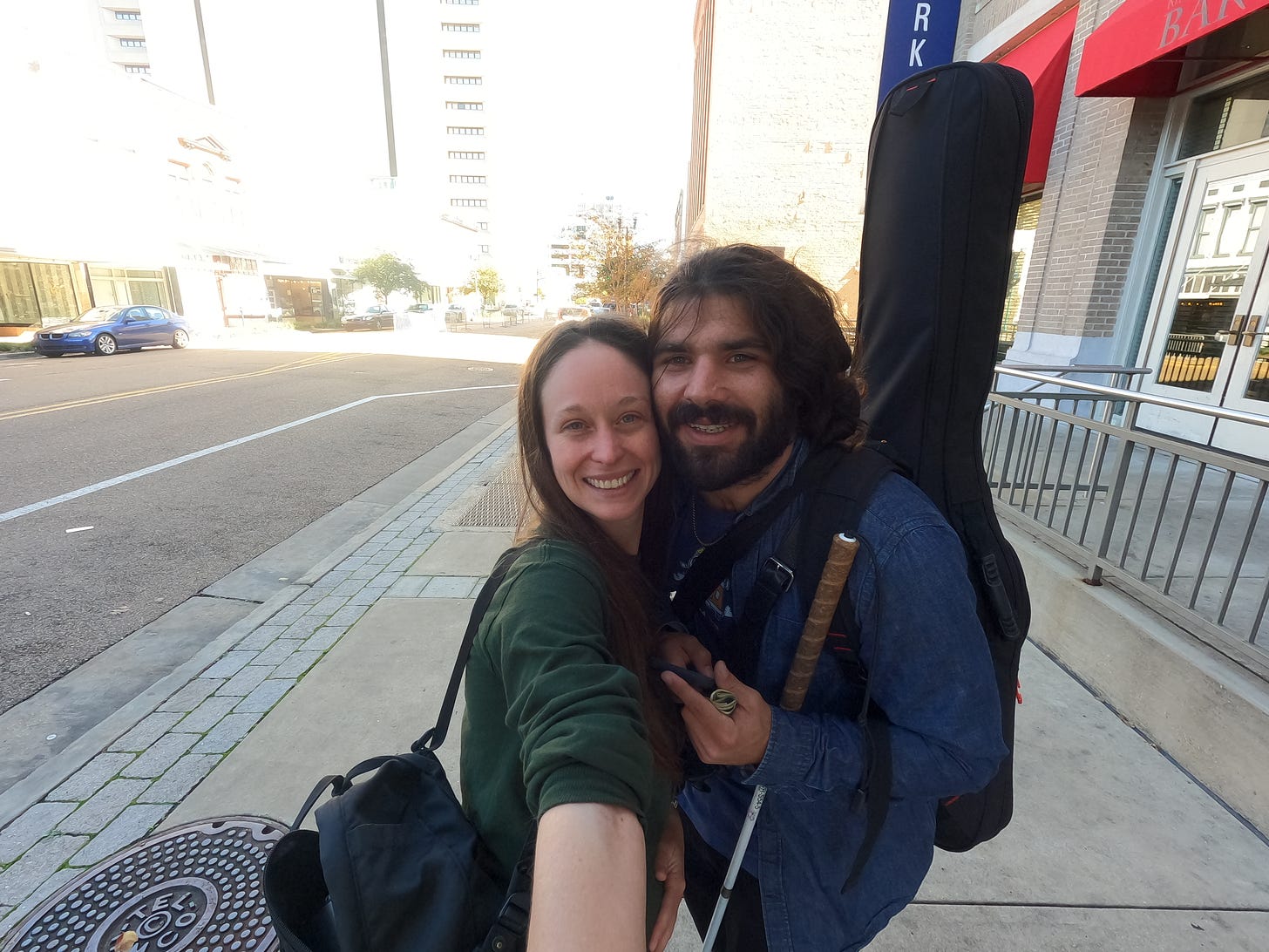 Kelly and Anthony smile so big as they wait for their car - anthony is holding his cane and they are hugging each other