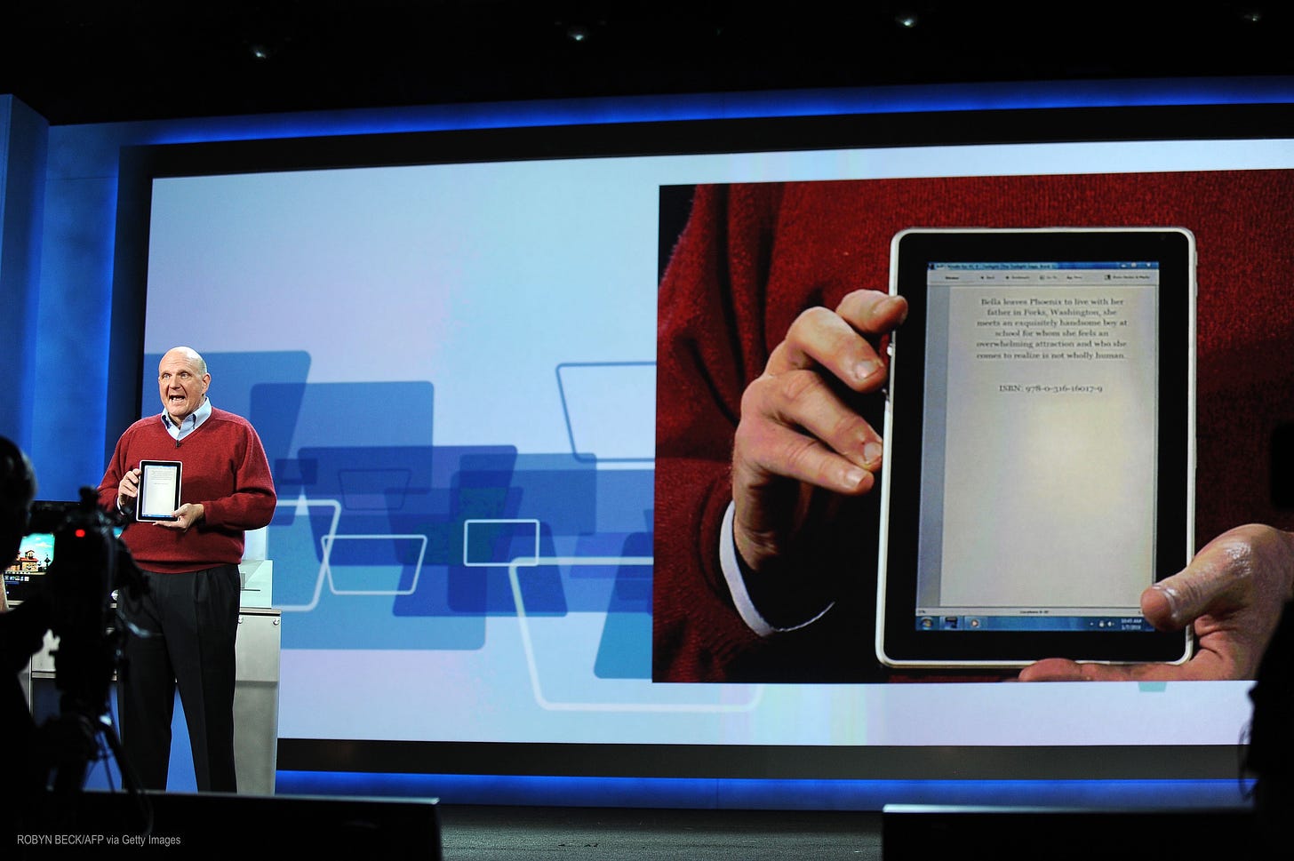 Steve Ballmer on stage showing the HP tablet running Windows 7. He is holding the tablet. Behind him is a giant screen showing a closeup. This is CES 2010.