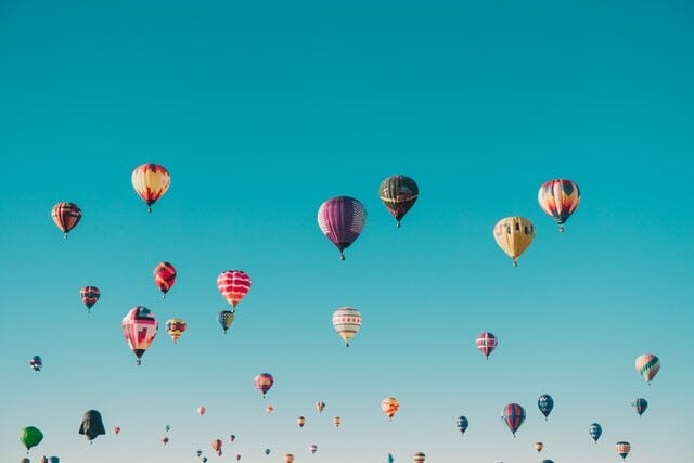 a group of colorful hot air balloons rising against a bright blue sky