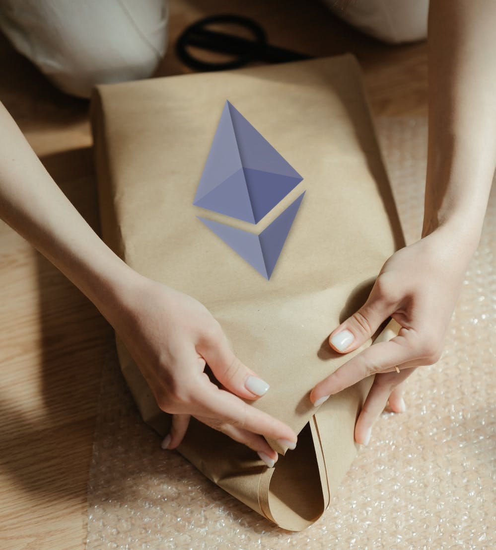 A person wrapping a box in brown paper with the ETH logo on it.