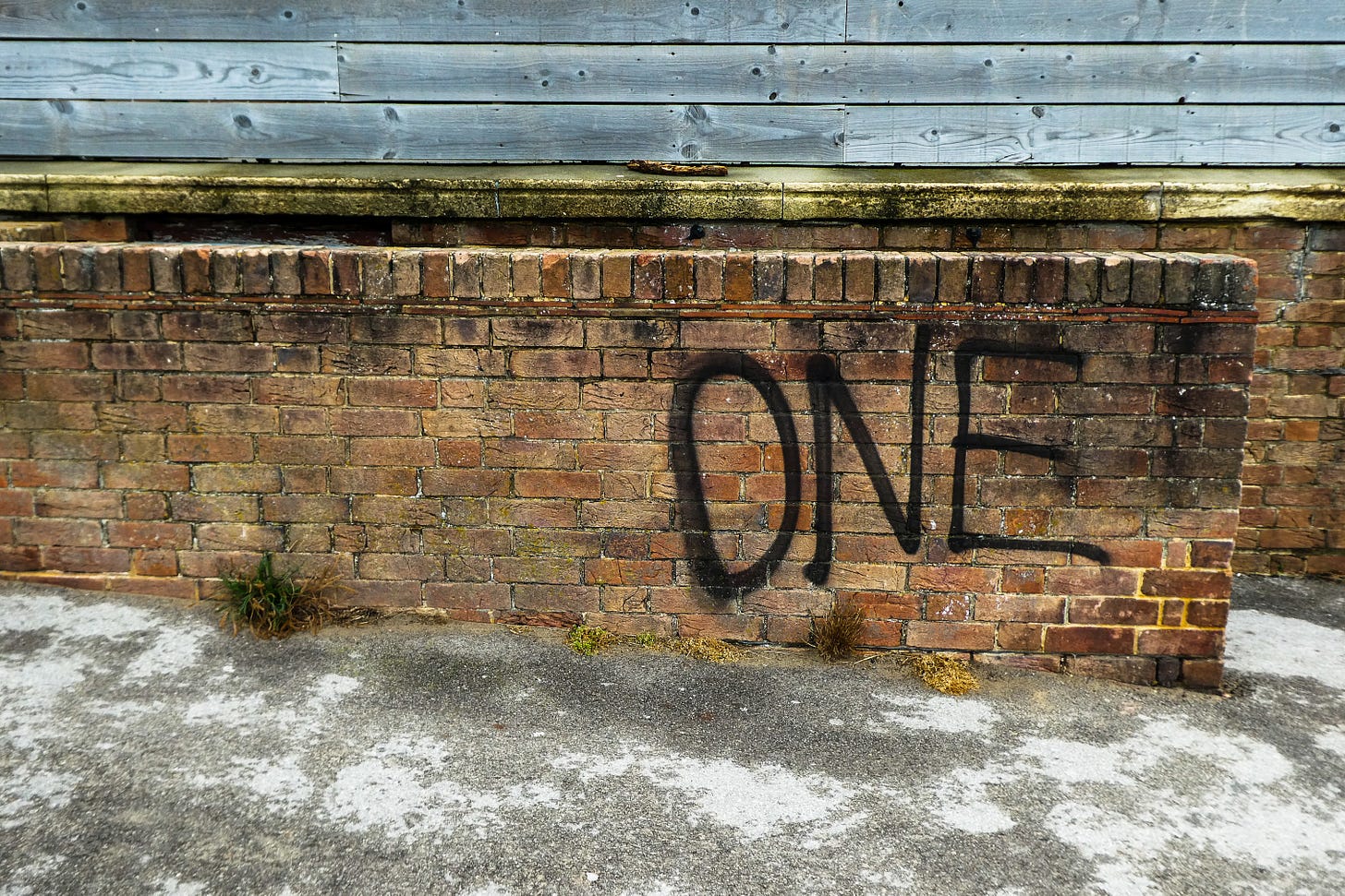 Brick wall with the word "one" spray painted on it in black