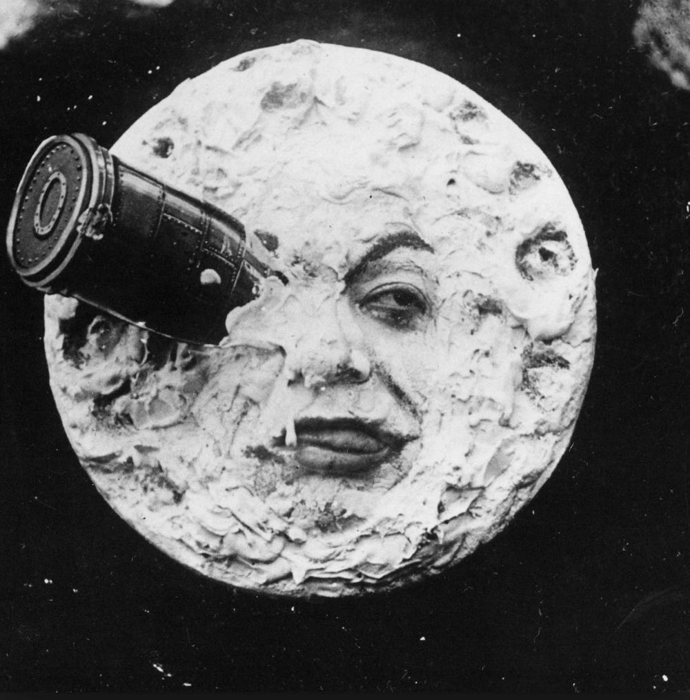 From “Le Voyage dans la Lune” (1902), a screenshot of the moon’s face, with a rocketship lodged in its left eye, its tongue slightly protruding from its lips