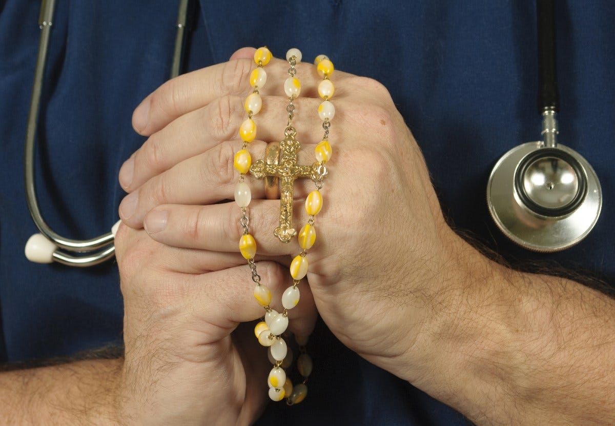 Catholic hospitals are wrecking reproductive health care | Person in scrubs holding a rosary