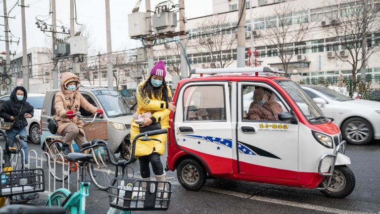 A woman exits a tiny car near a subway station in Beijing.