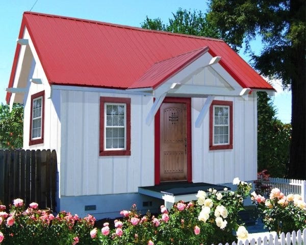A tiny white house with red trim