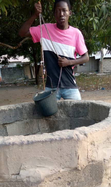 The author pulls water from a well in Brikama.