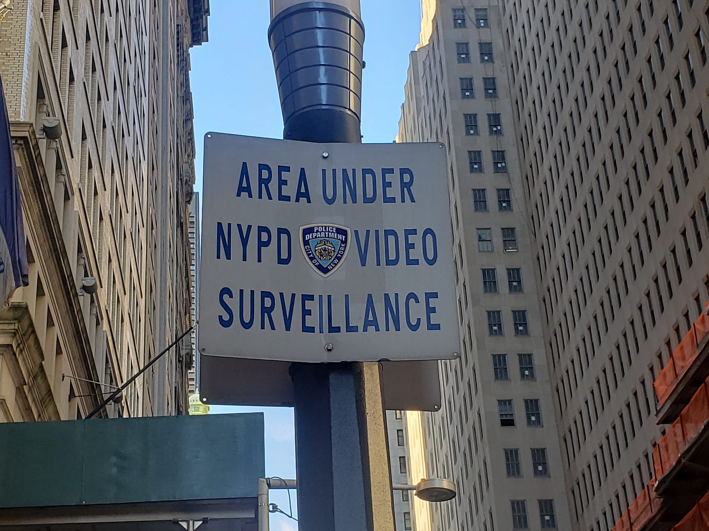 A photo of a sign with the NYPD shield, which states Area Under NYPD Video Surveillance