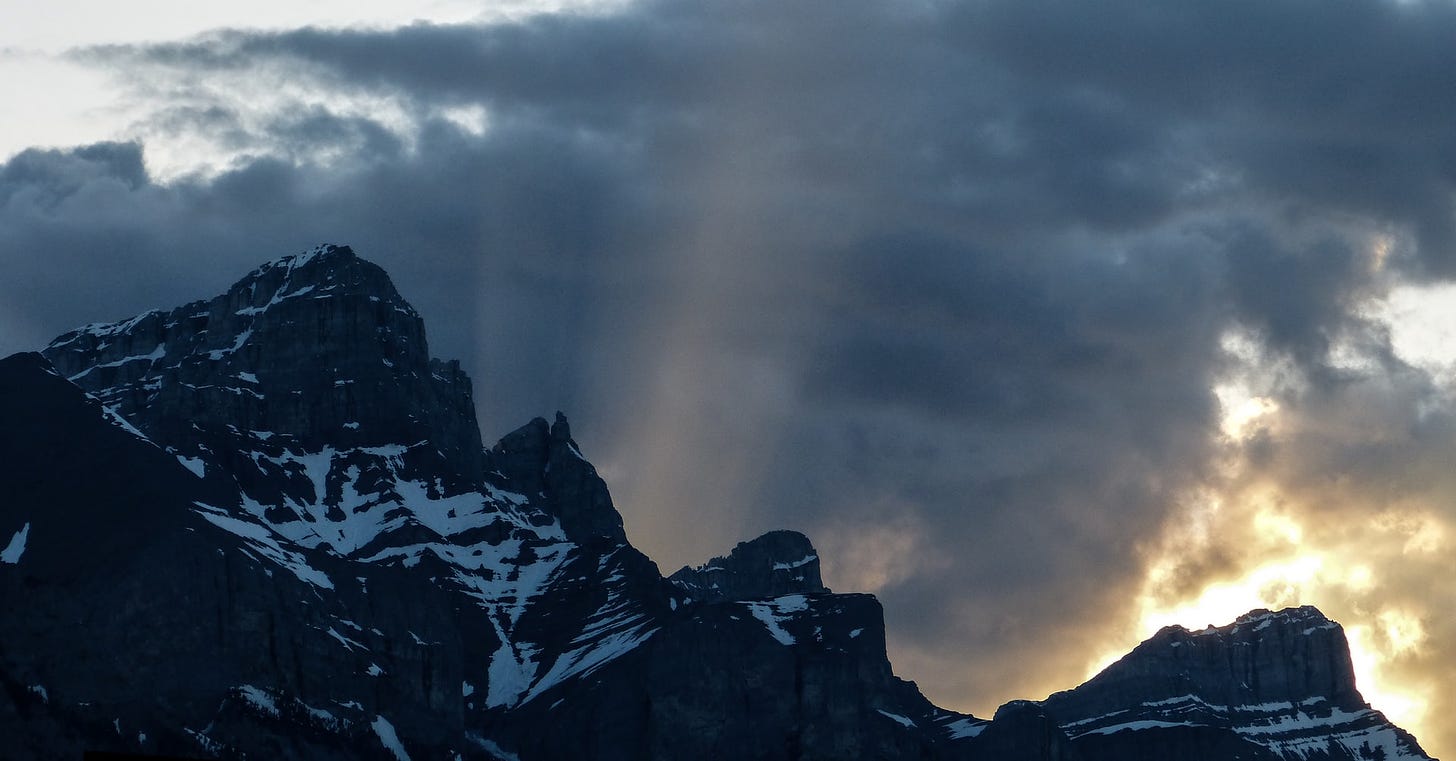 Sunbeams caused by the setting sun - mountain tops and clouds, Canmore, Canada