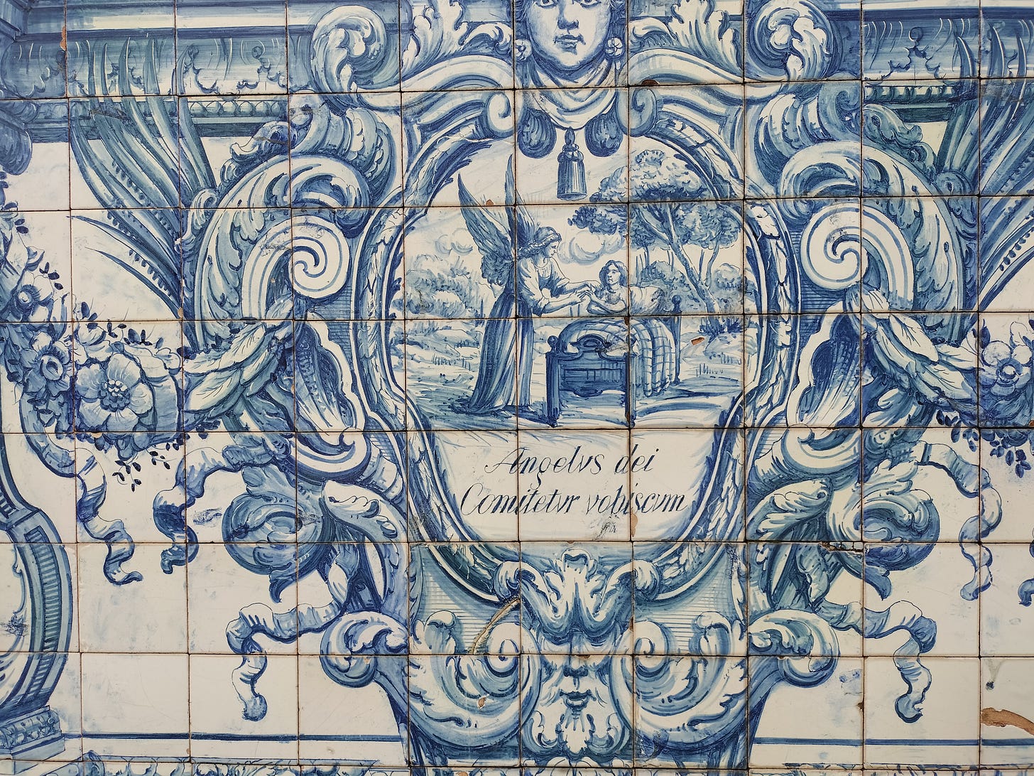 blue and white tiles with an image of an angel comforting a person in a bed. The bed is outdoors