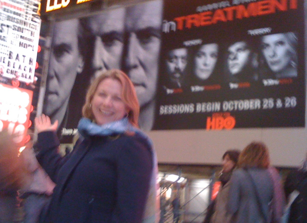 A blonde woman points at Gabriel Byrne on a billboard near Times Square