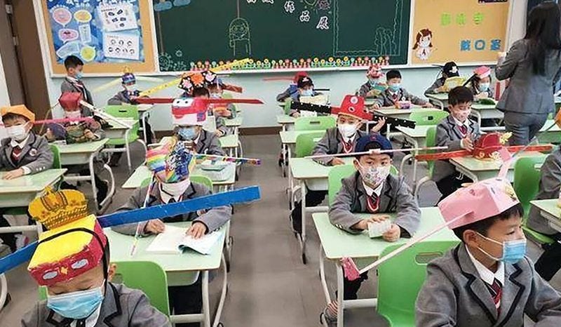 Grade school students in the east end Hangzhou area are fashioning wide hats made from materials including balloons to keep others at least three feet away, according to the South China Morning Post.