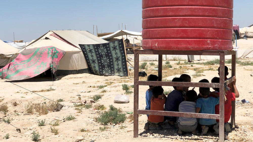 Children shelter from the sun at northeastern Syria's al-Hol camp in May. The camp is now home to nearly 69,000 people.
